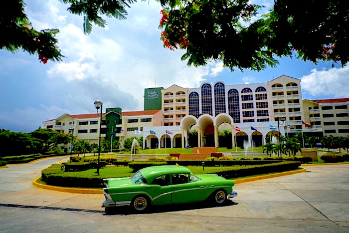 A vintage car passes in front of the Four Points by Sheraton hotel in Havana, Tuesday, June 28, 2016. American hotel giant Starwood has begun managing this hotel run by the Cuban military, opening one of the biggest holes in the U.S. trade embargo on Cuba since Presidents Barack Obama and Raul Castro declared detente in Dec. 2014. (AP Photo/Ramon Espinosa)